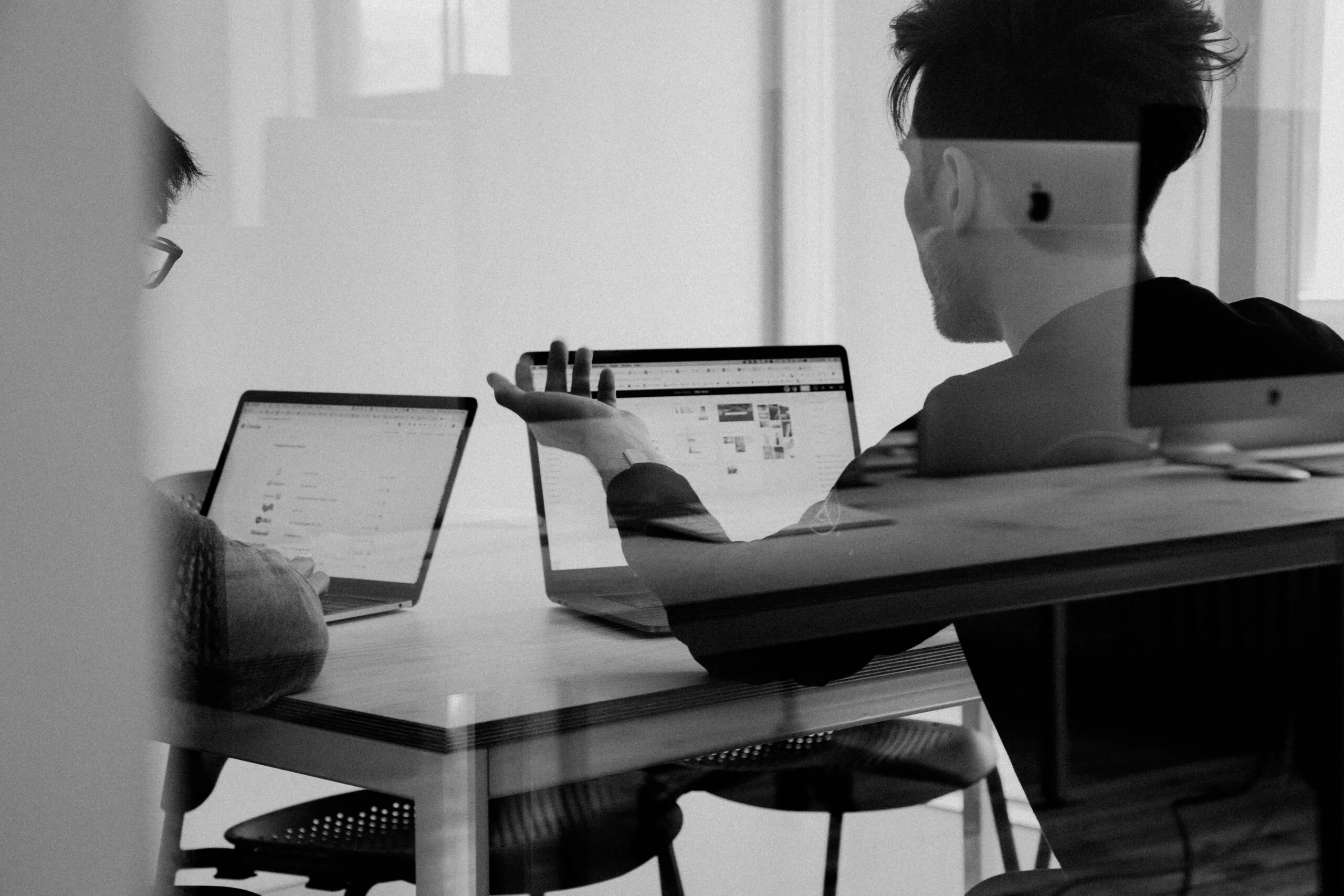 Zwei Personen, die gemeinsam an Laptops arbeiten, symbolisieren die Zusammenarbeit zwischen Kunde und Entwickler